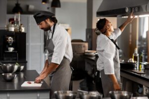 Le migliori attrezzature per cucine. Foto che mostra 2 chef a lavoro in una cucina professionale di un ristorante. 